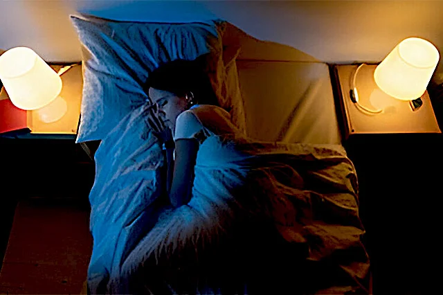 A beautiful women sleeping in a bedroom with blue & white lights.