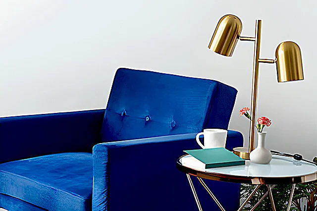 A golf brass table lamp on the side table near blue sofa