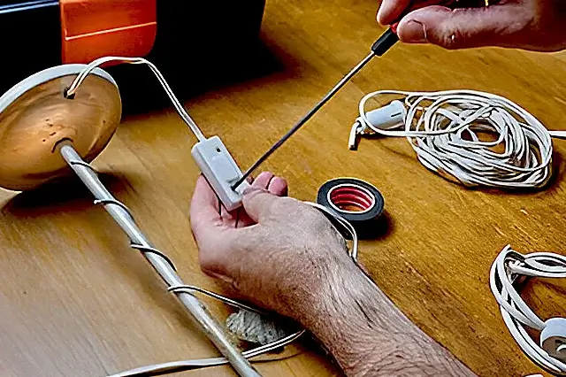 electrician opening the screw of table lamp to fix lamp switch faults