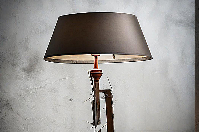 A modern black floor lamp with oval lamp shade in front of a wall