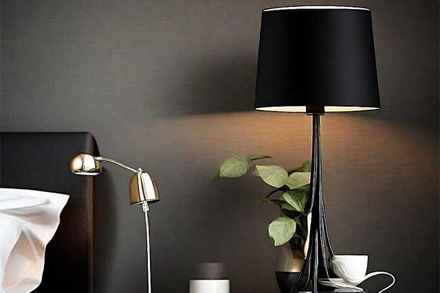 A black table lamp on a bed side table