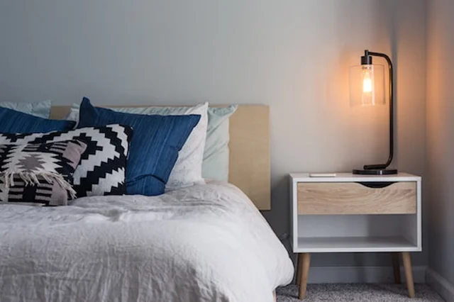 table lamp on a table shedding golden light near the bed side.